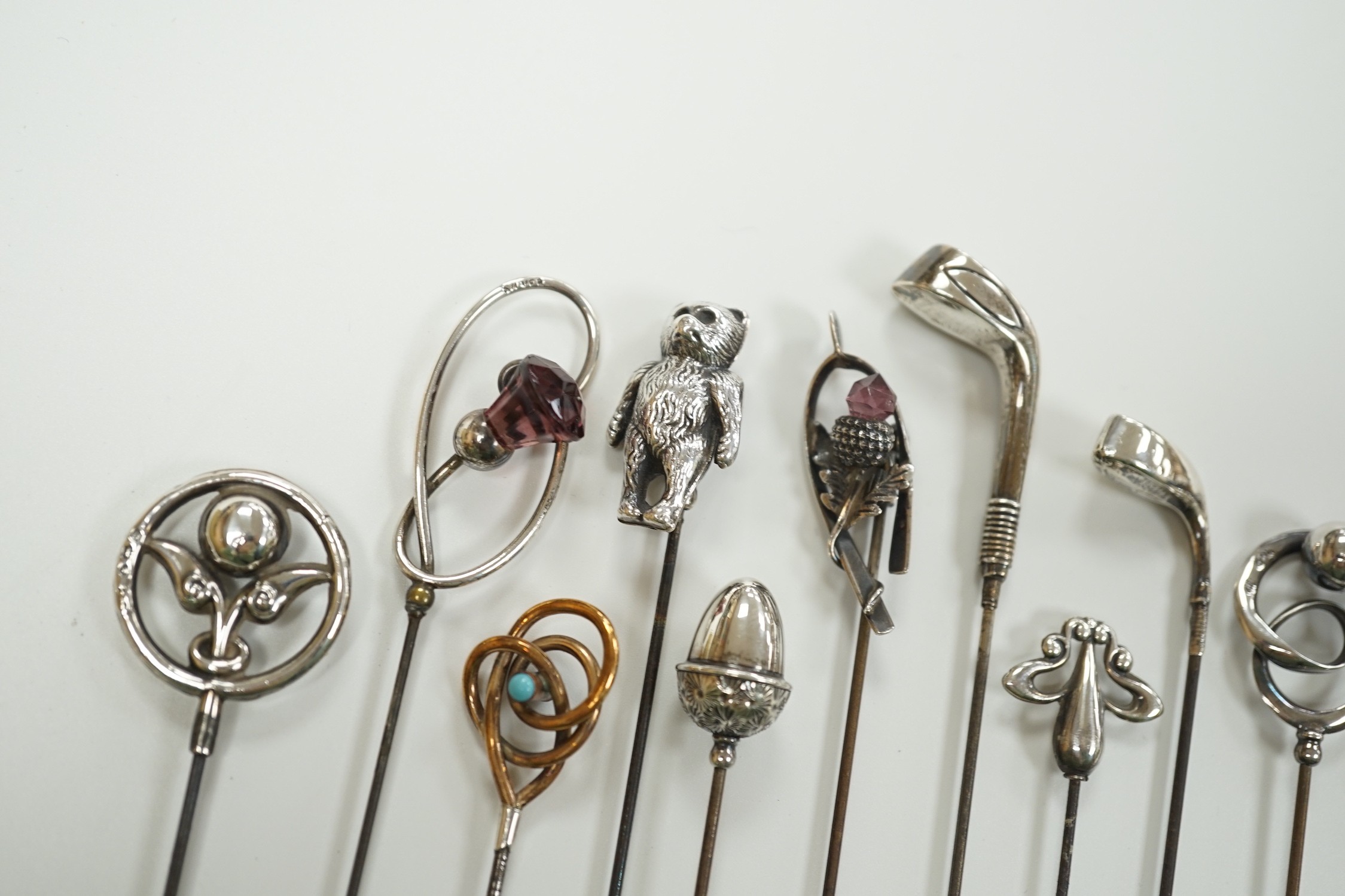 A collection of thirteen assorted early 20th century and later white or yellow metal hat pins, including four by Charles Horner including teddy bear and two silver golf club, longest 31.5cm.